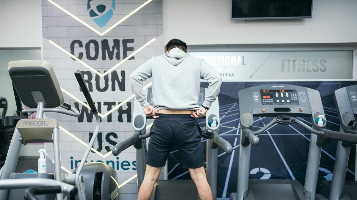 Homem correndo na esteira em uma academia