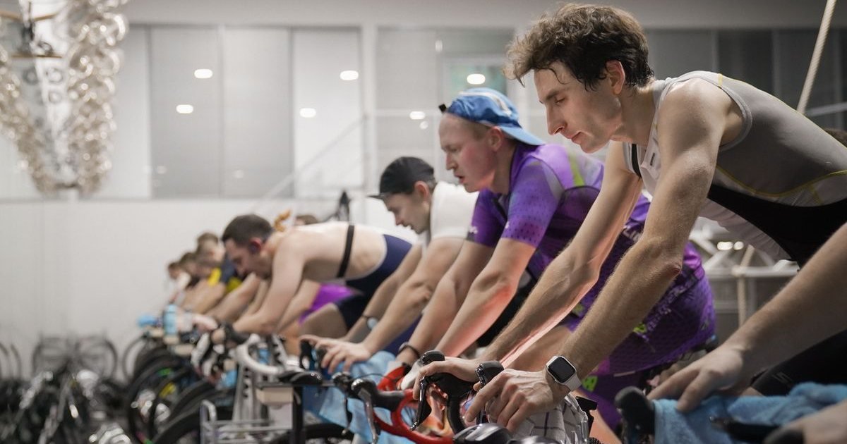 Turma pedalando em bikes indoor durante uma aula de ciclismo