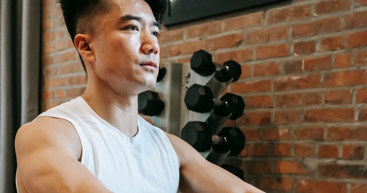 Homem treinando em uma máquina de remo indoor numa academia