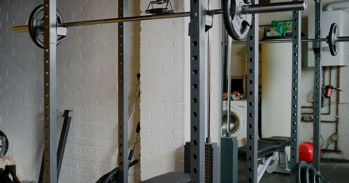 Home gym com rack, barra e banco de supino, ambiente típico para uma smith machine