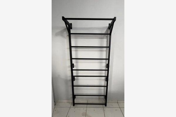 Espaldar de aço preto com barra de tração, em fundo claro e piso de cerâmica