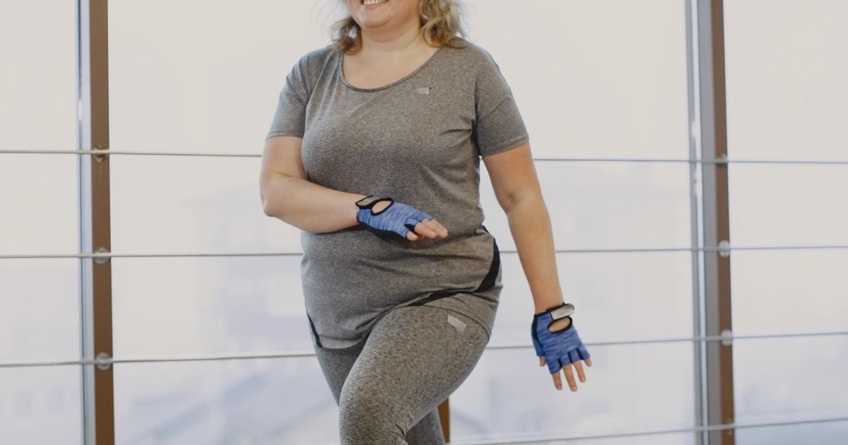 Mulher de luvas durante exercício aeróbico em uma sala ampla