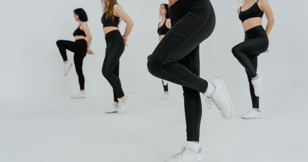 Mulheres em fileira levantando o joelho em um estúdio branco