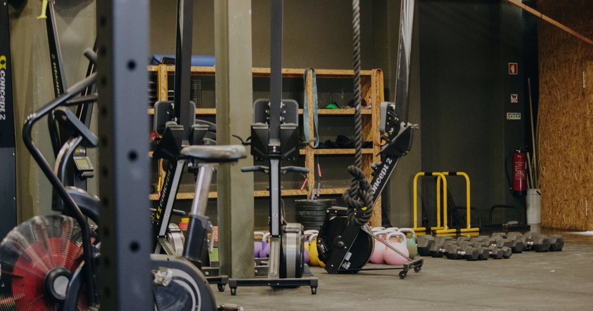 Equipamentos de academia, entre eles bicicletas, organizados em um salão de treino