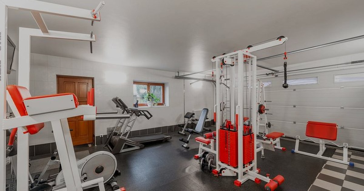 Sala de ginástica em casa com equipamentos de treino e piso emborrachado