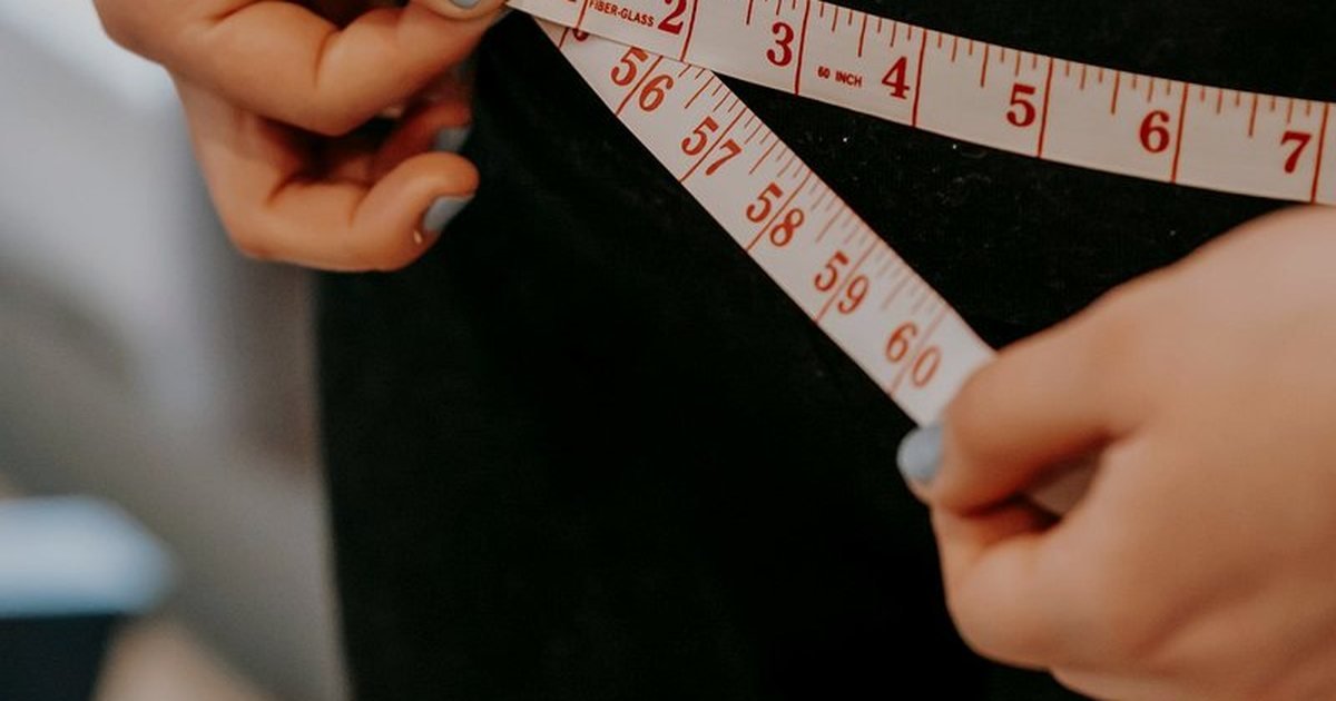 Fita métrica ao redor da cintura de uma pessoa que acompanha o emagrecimento