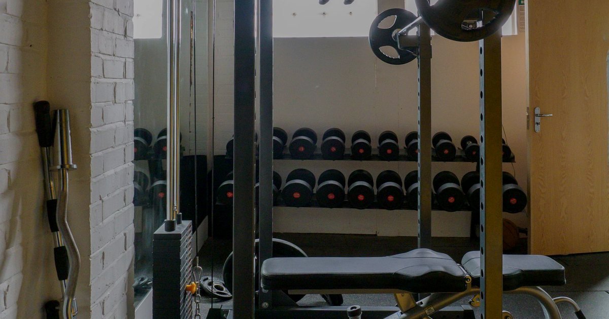 Rack de halteres e banco em uma sala de treino de força