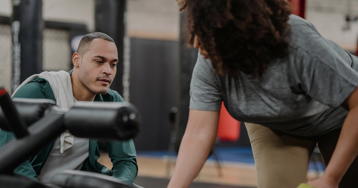 Treinador orientando uma aluna em exercício de reabilitação numa academia