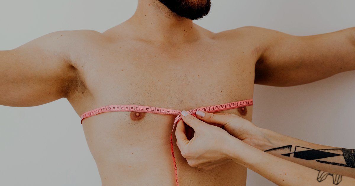 Profissional medindo a circunferência do peito de um homem com fita métrica