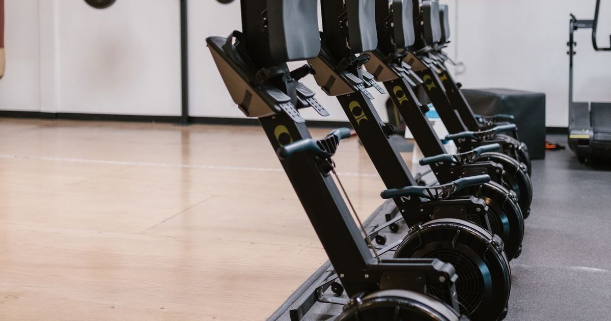 Fileira de máquinas de remo indoor em uma academia ampla