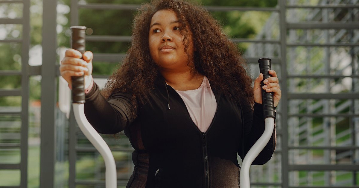 Mulher em uma academia segurando as manoplas de um aparelho de movimento de pernas e braços