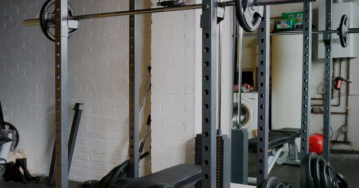 Rack de musculação com barra e anilhas em uma sala de treino em casa